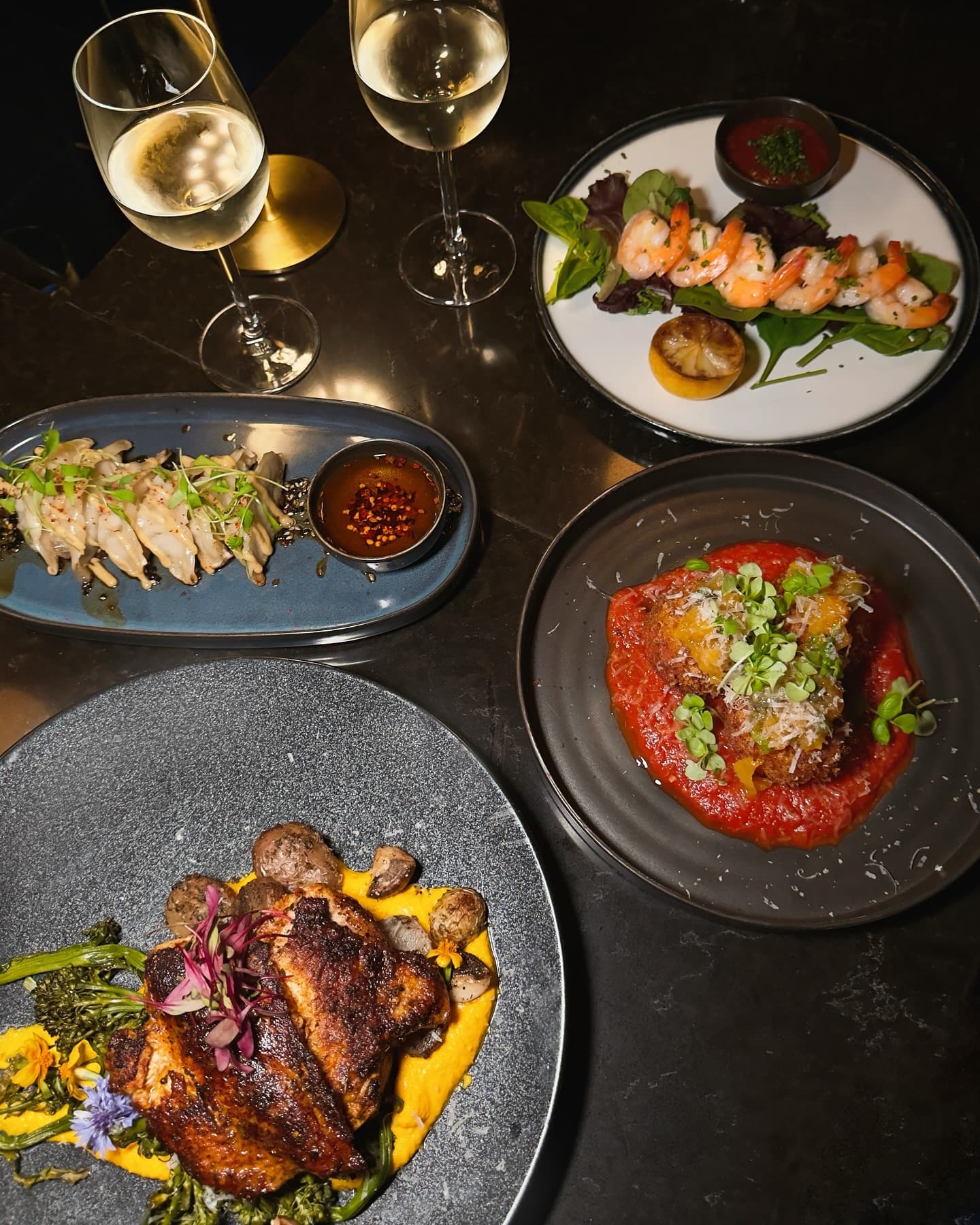 Table spread of plates and white wine at Somewhere Dine Bar