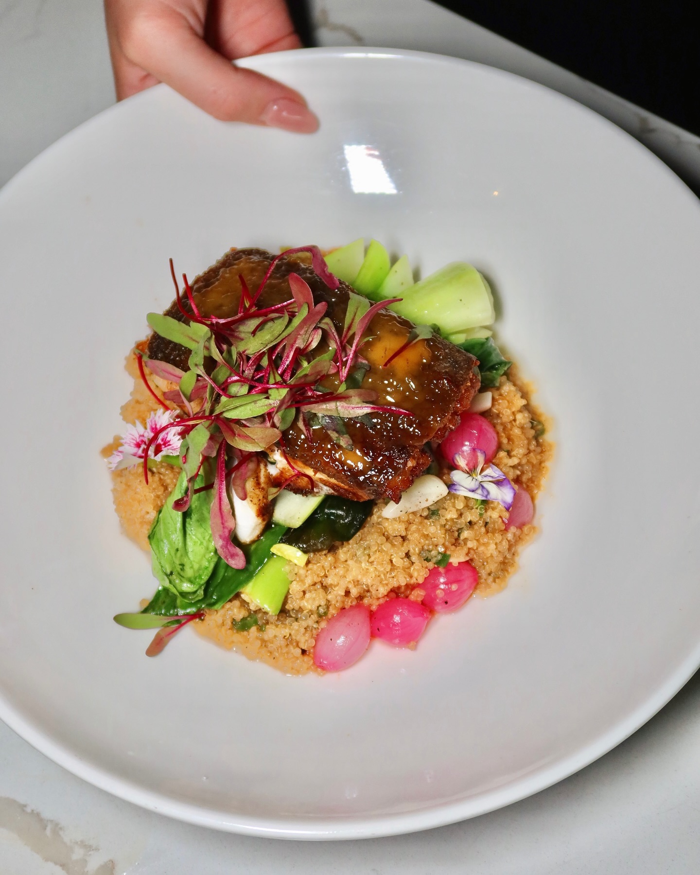 Glazed fish with grains and vegetables in a bowl at Somewhere Dine Bar
