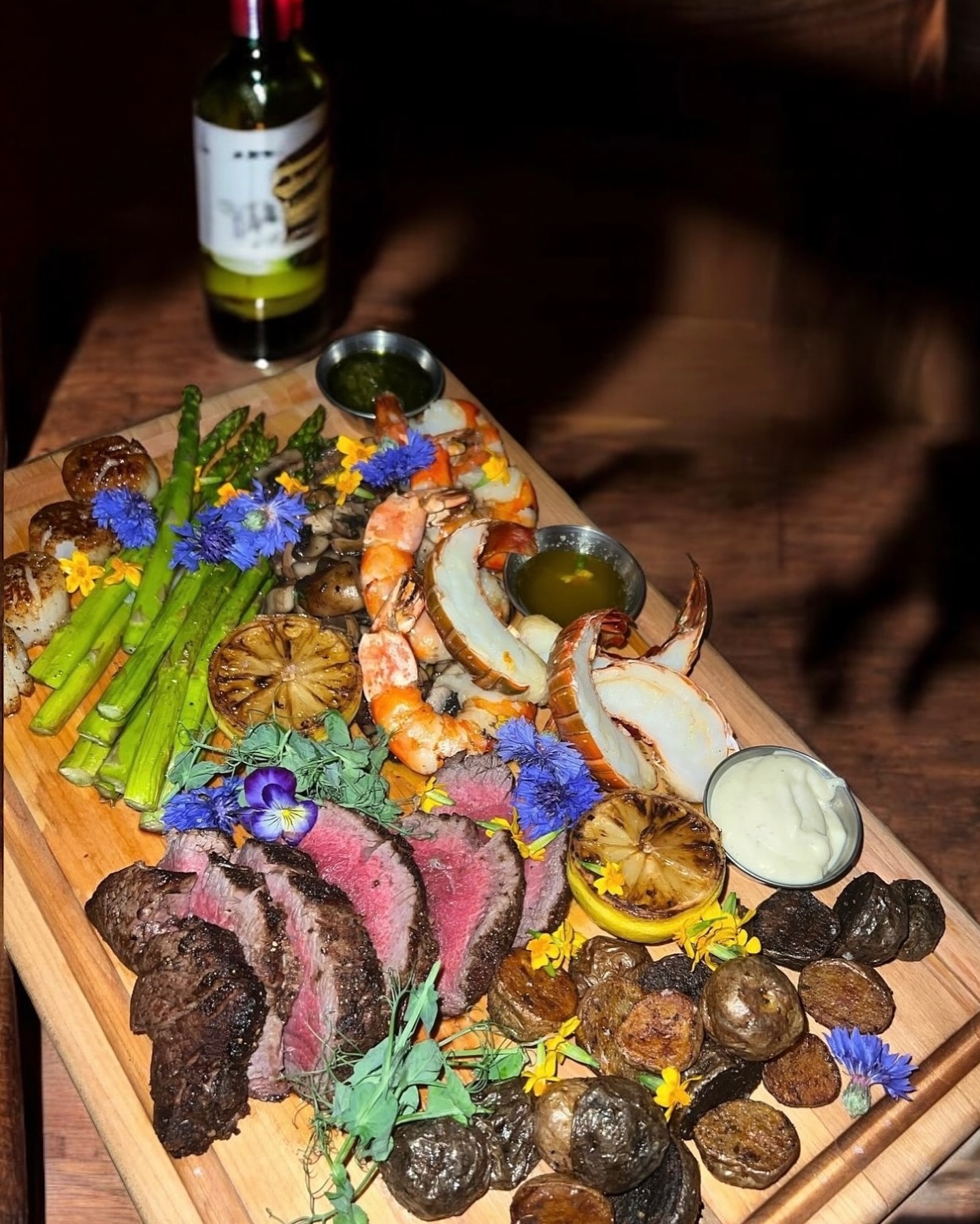 Surf and turf sharing board with seafood, steak, and sauces at Somewhere Dine Bar