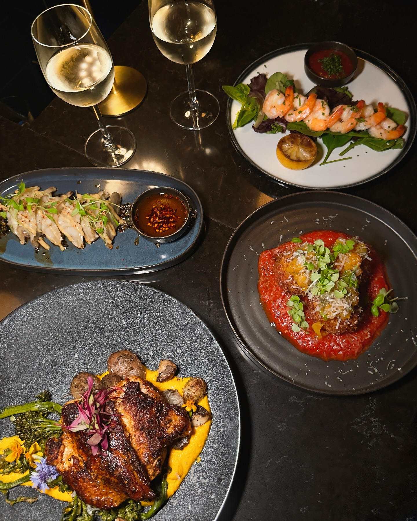 Table spread of plates and white wine at Somewhere Dine Bar